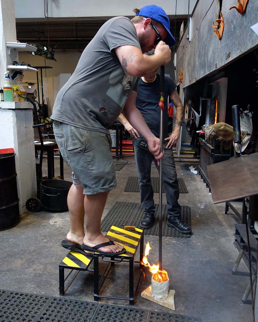 alt="Glassblower Kyle Herr tests the mold"